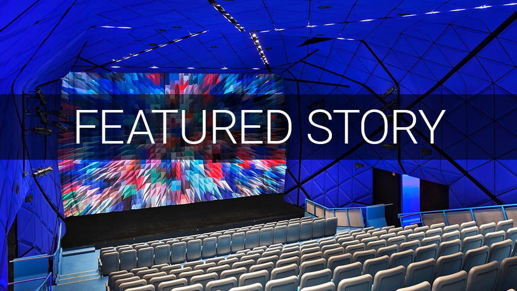 Empty blue auditorium with large screen showing colorful abstract art, and "FEATURED STORY" text.
