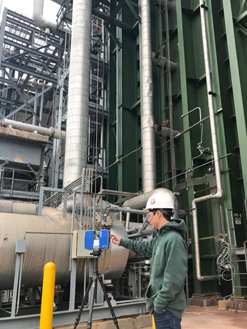 Man pointing at a 3D scanner in an industrial plant.