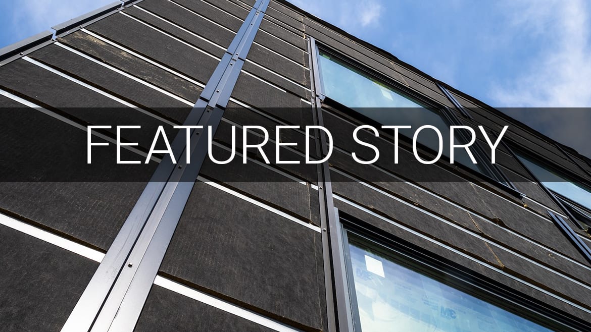 Modern building facade with dark panels, metal accents, windows, and sky. 'FEATURED STORY' text.