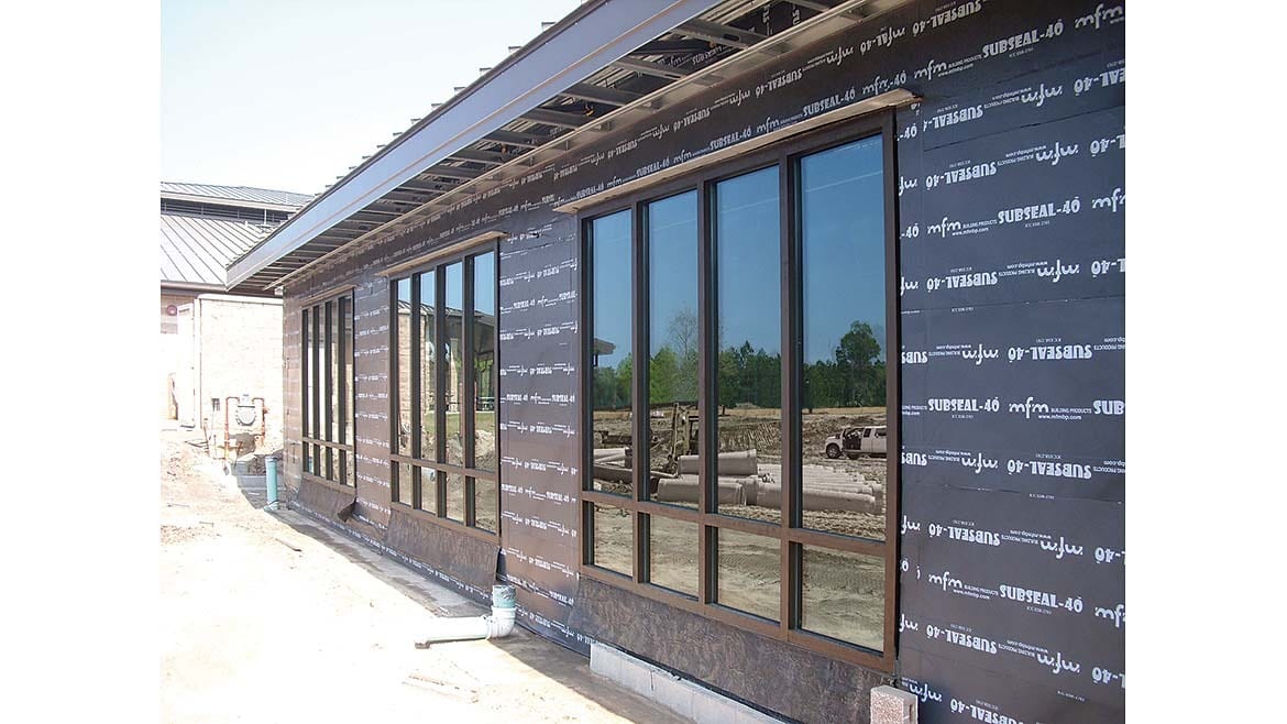 Building under construction: black SUBSEAL-40 mfm weather barrier, windows.