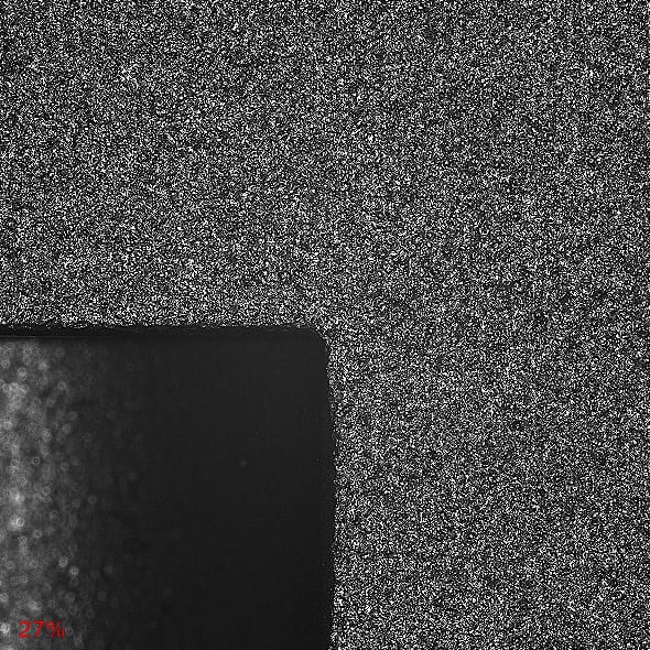 Dark rounded corner of a dark shape against a speckled background, with "27%" text.