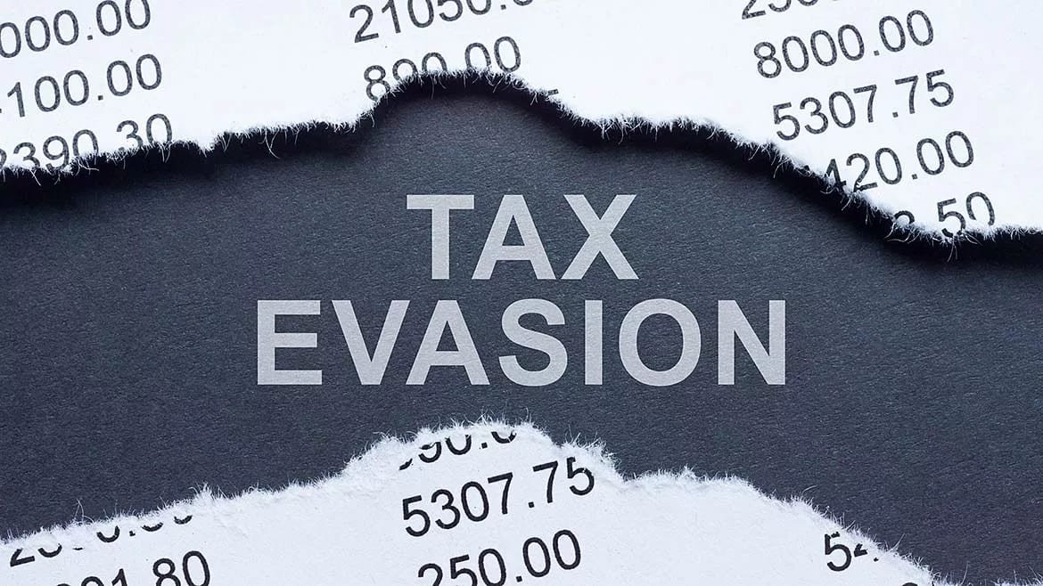 The phrase "TAX EVASION" is prominently displayed on a dark background, framed by torn white paper showing financial numbers, symbolizing financial illicit activity.