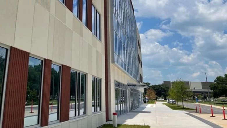 Modern building exterior with large windows and light siding under a cloudy sky.