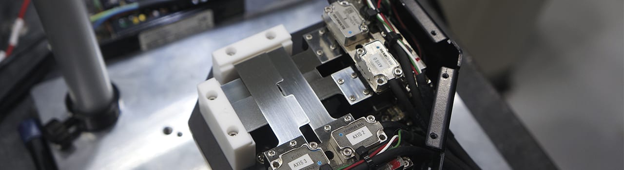 Close-up of complex industrial machinery with metal components, Renishaw sensors (AXIS 2, AXIS 3), and wires.
