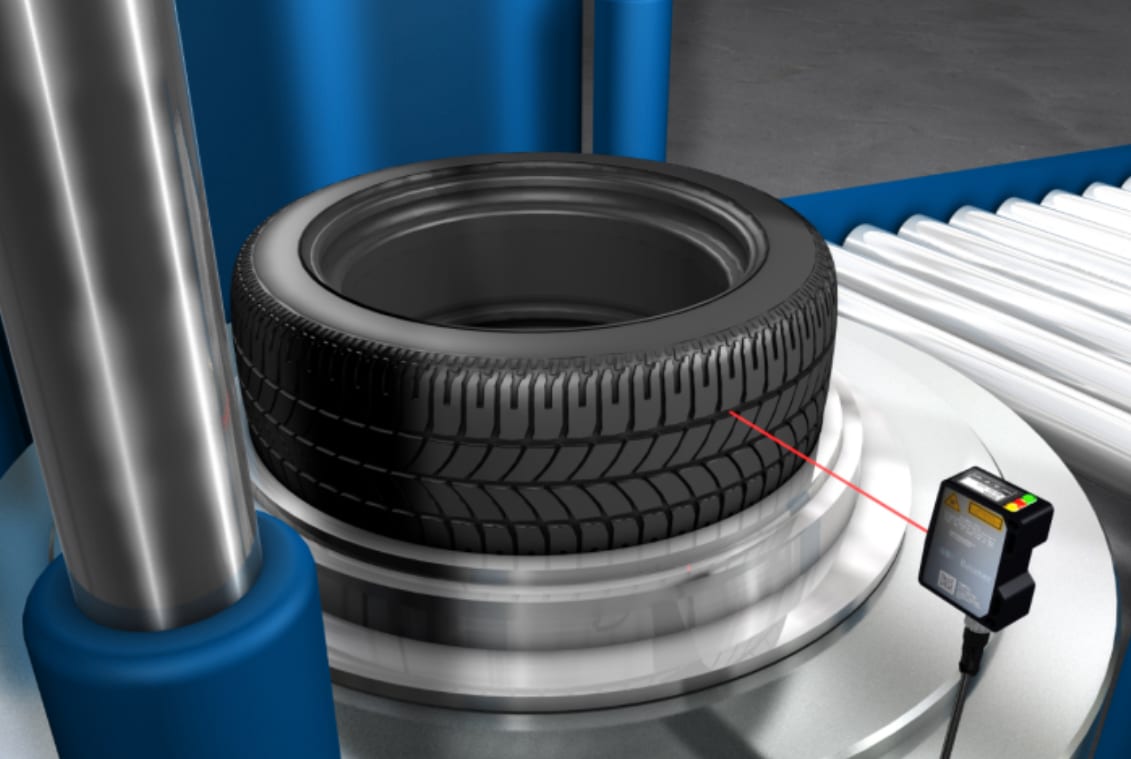 An industrial laser sensor inspecting the tread of a tire on an automated production line.