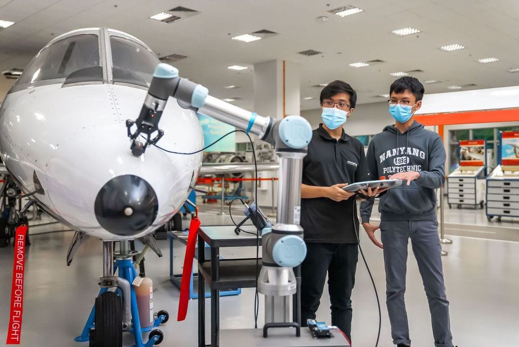Two workers using cobot to inspect jet