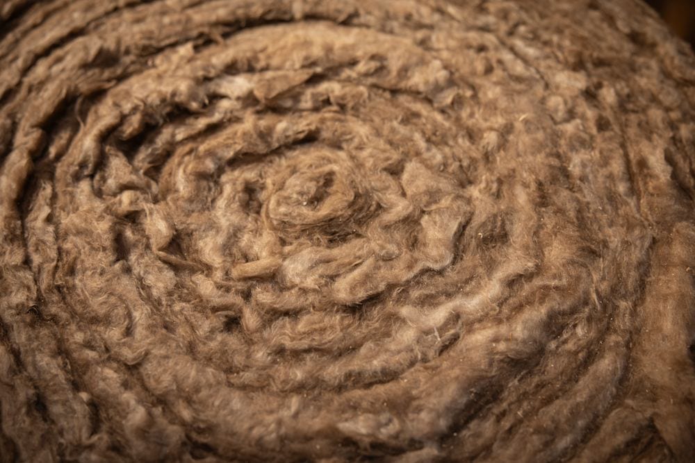 Close-up of brown rolled fibrous material, like insulation or a natural fiber mat, showing texture.