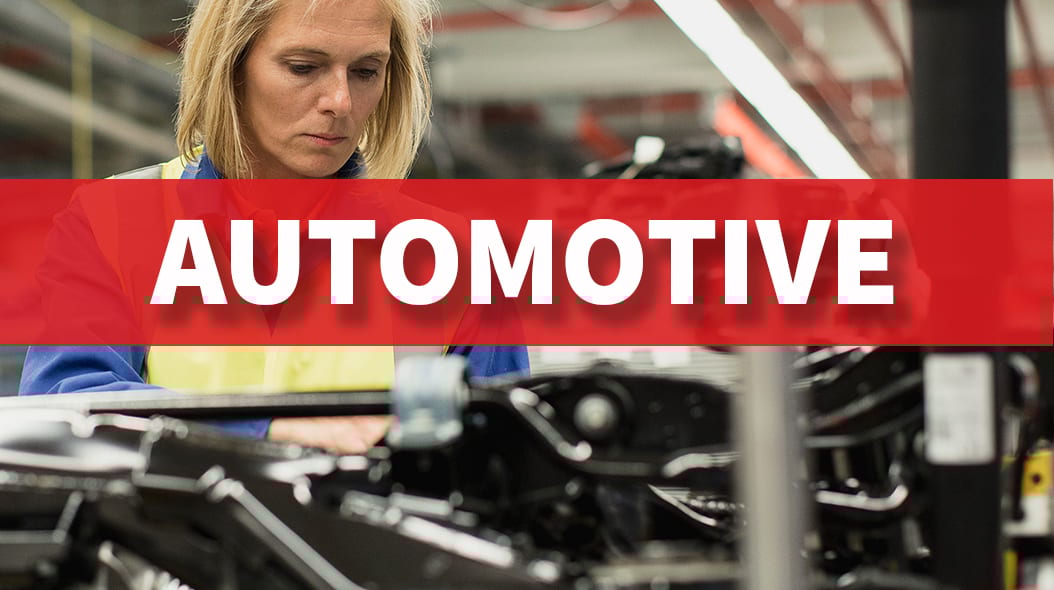 Woman working in factory with "AUTOMOTIVE" banner.