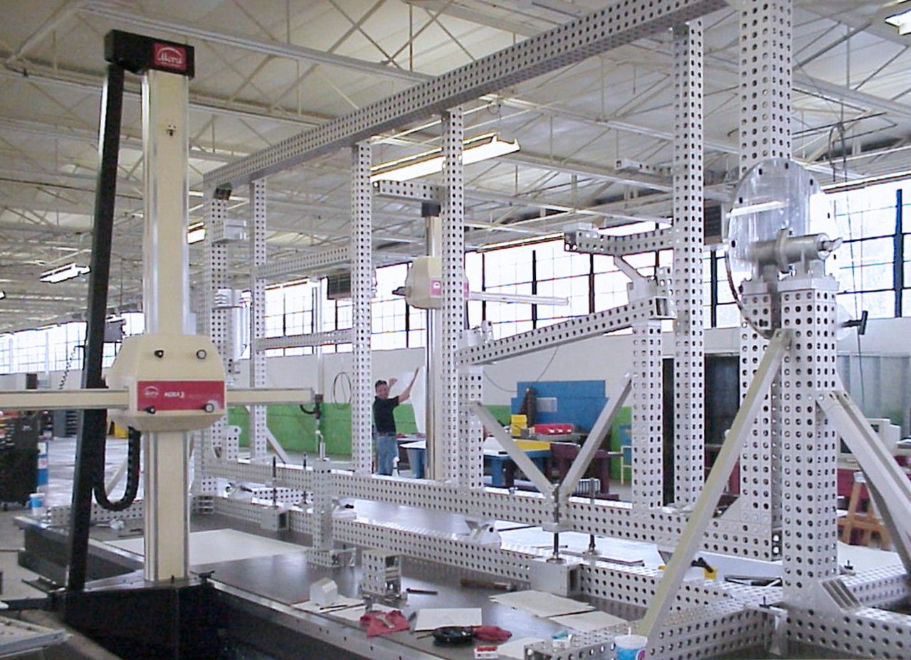Large CMM machine in an industrial space, surrounded by a complex perforated metal framework.