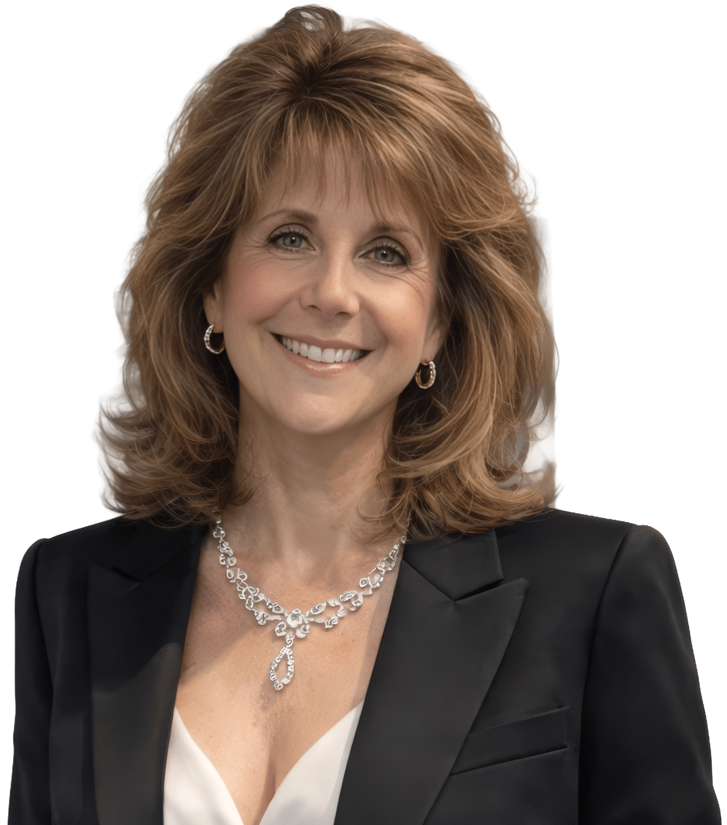 A smiling woman with brown hair and a sparkling necklace wears a black blazer over a white top.