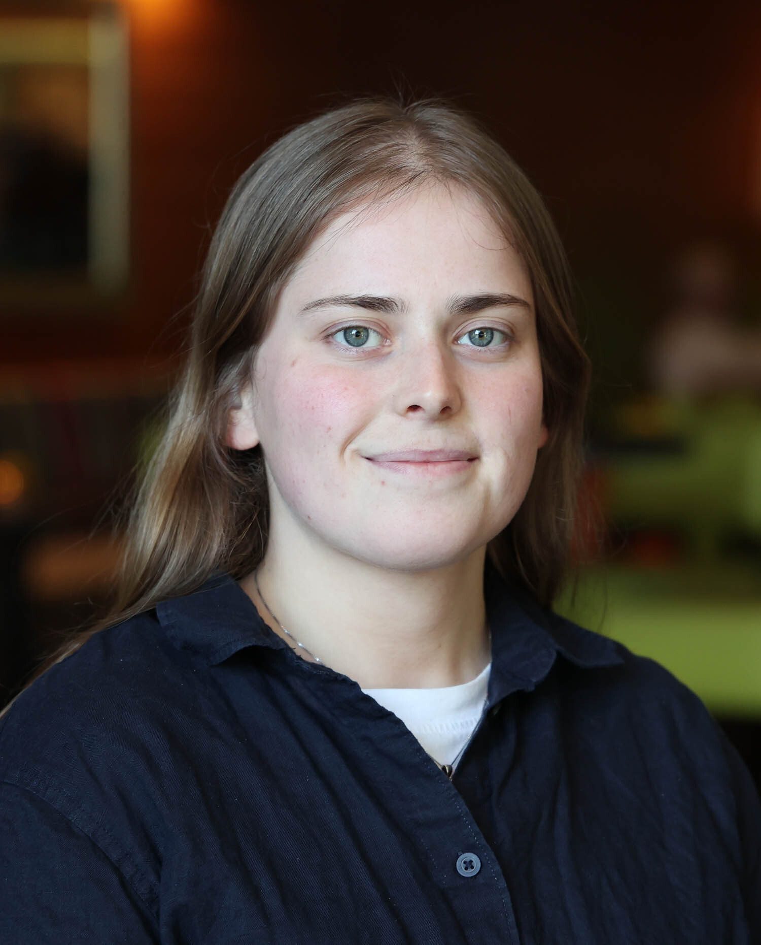 Portrait of a smiling young woman with long hair and blue eyes.