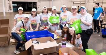 team of people standing with cardboard boxes of food donations
