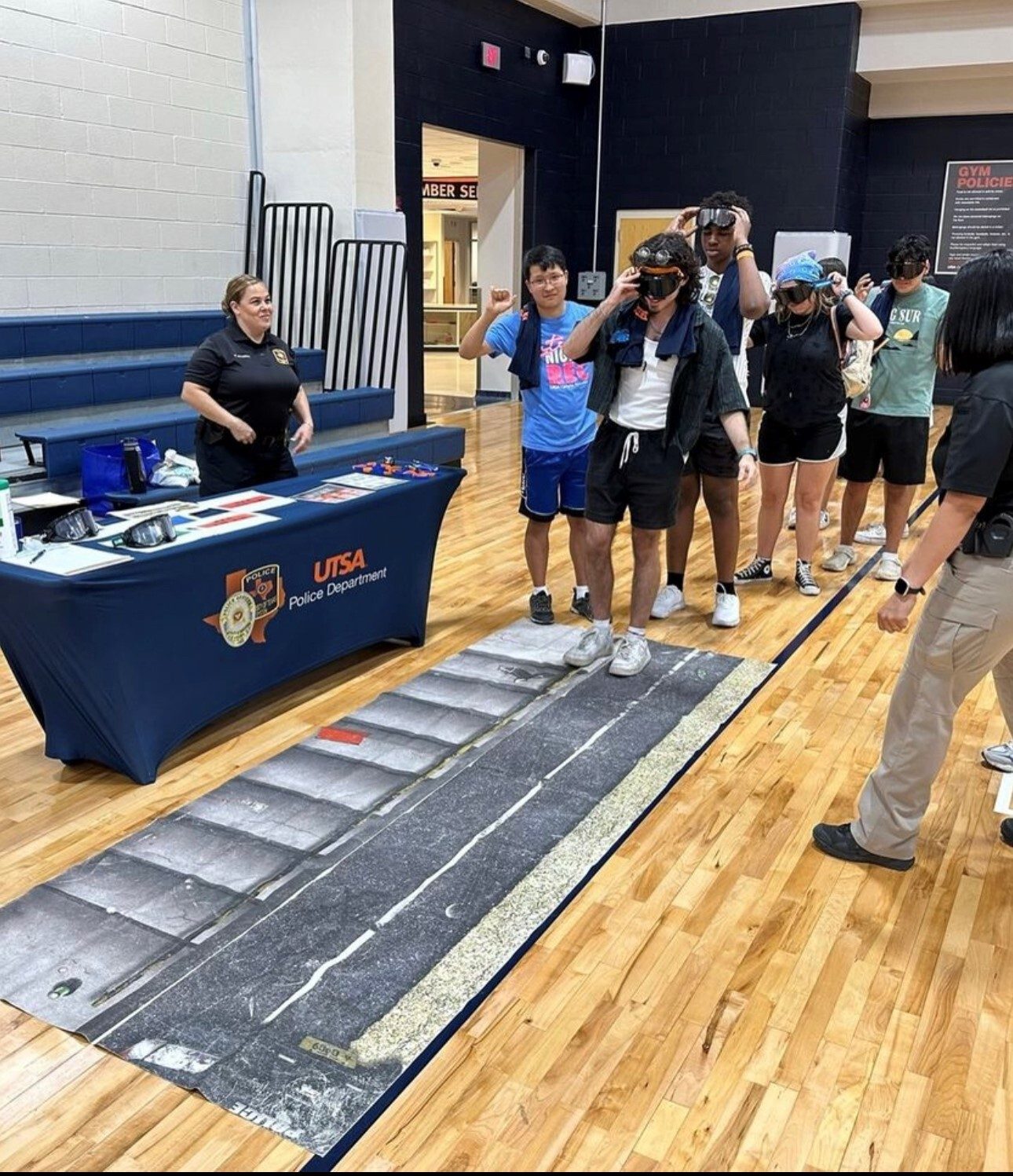 Students in line taking turns wearing drunk goggles and walking in a straight line
