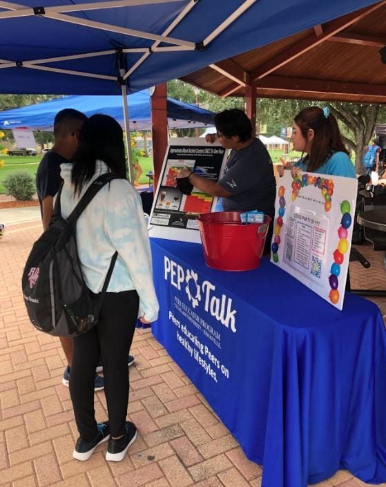 Students reading board discussing dangers of impaired driving at booth during safety event
