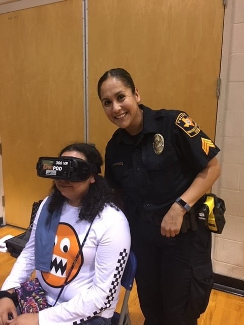 Campus police officer posing with student wearing VR goggles