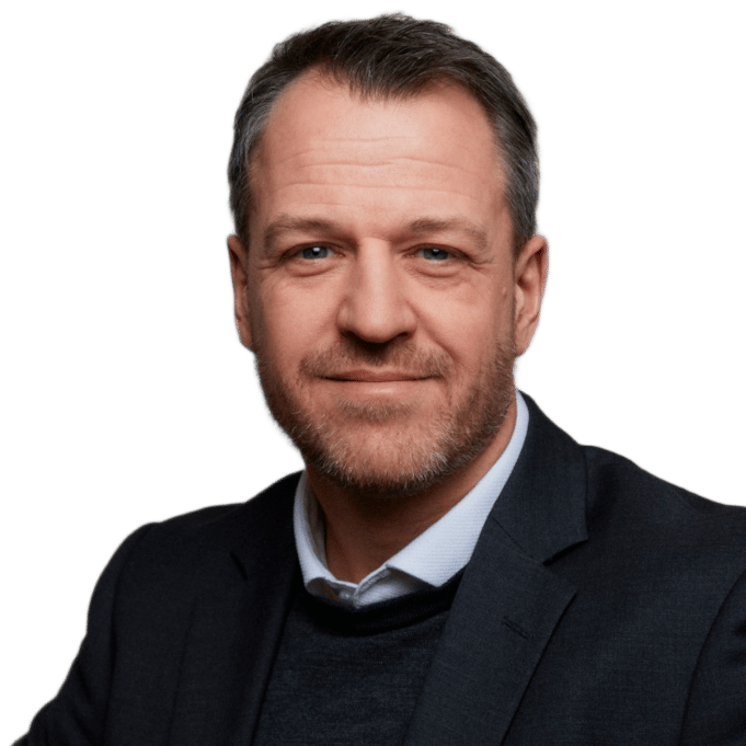 Headshot of a smiling man with a beard and graying hair, wearing a suit jacket.