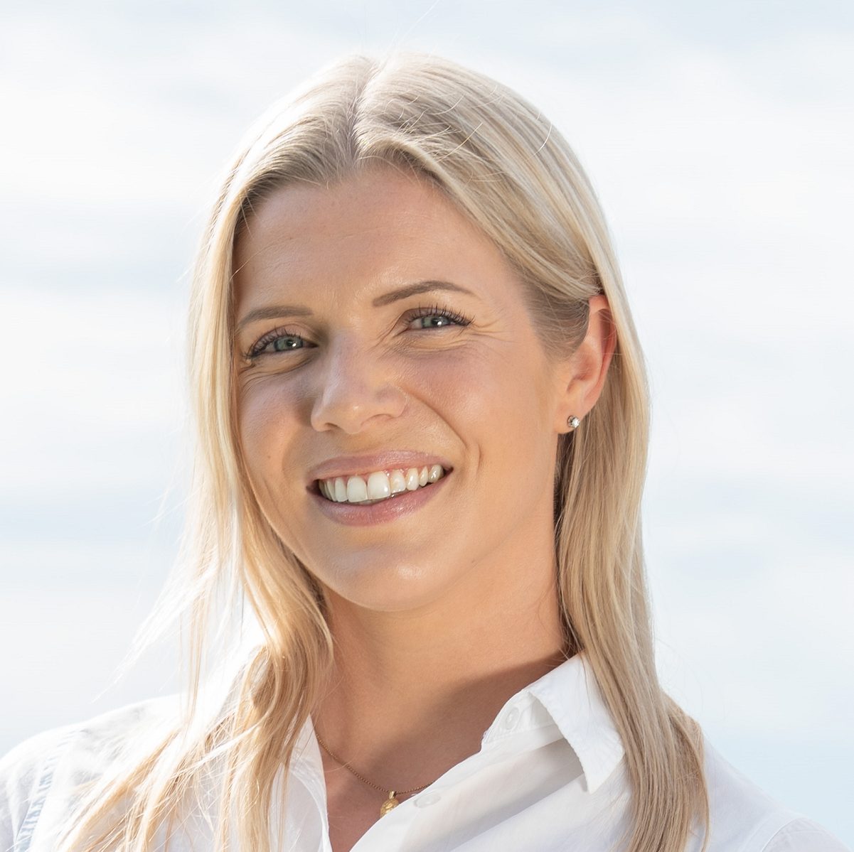 Headshot: Smiling blonde woman with long blonde hair, wearing a white shirt.