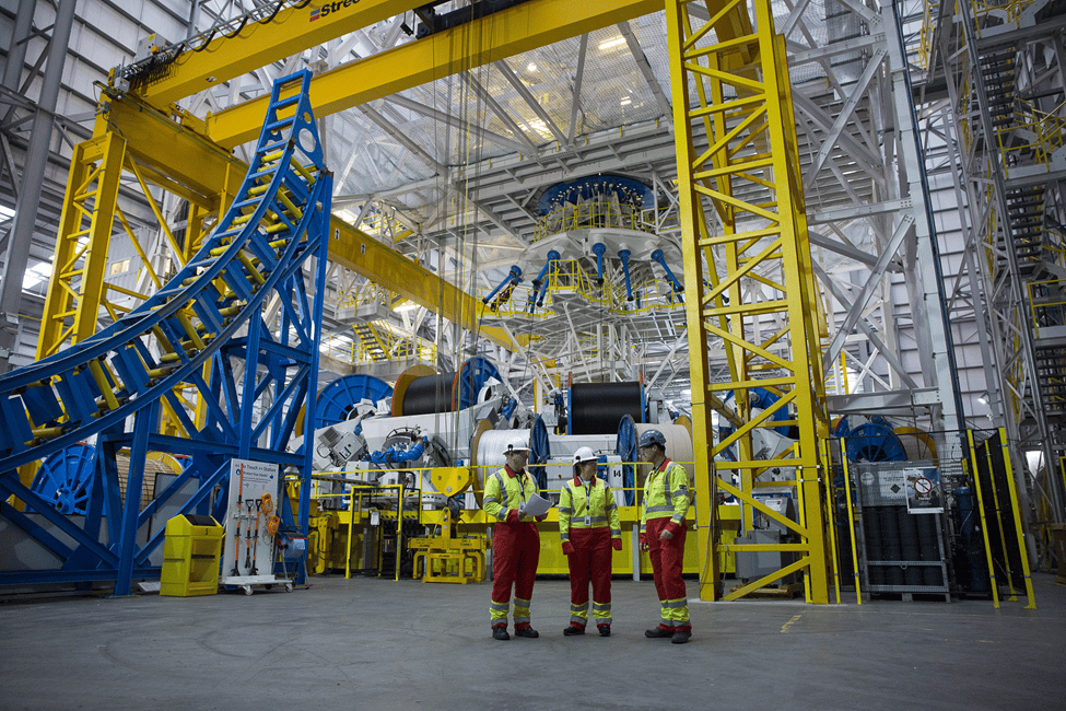 Three workers stand together at TechnipFMC&#x27;s facility in Newcastle where cable is manufactured for floating offshore wind.