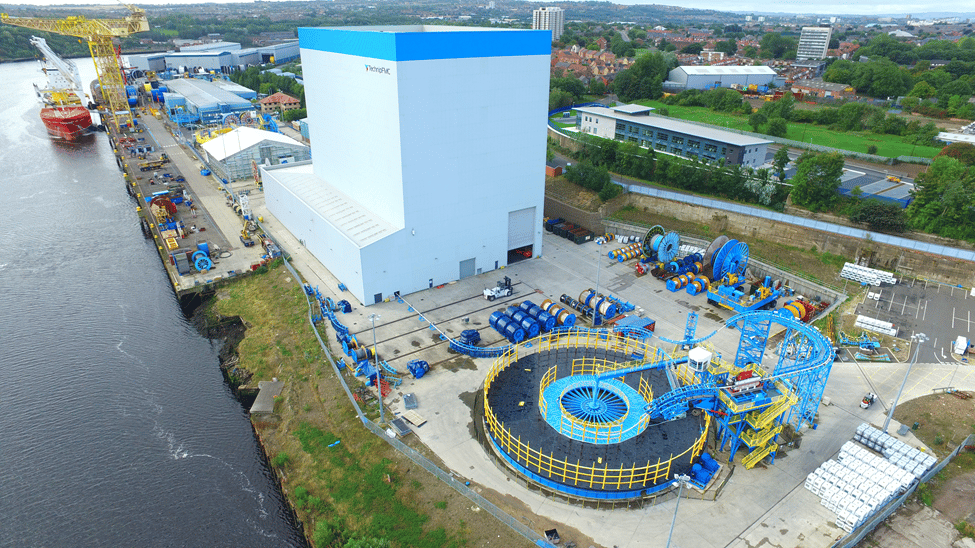 A vessel on a river is docked next to a large industrial facility.