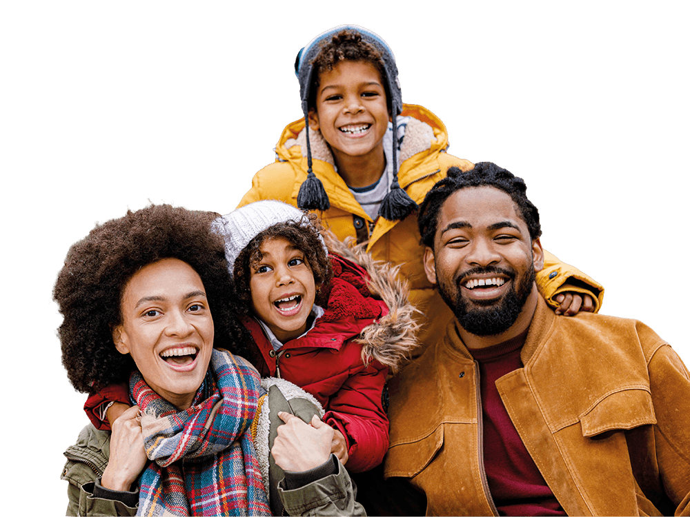 A joyous family of four, parents and two children, smiling broadly in warm winter attire.