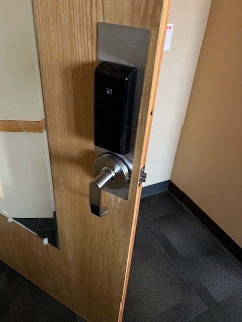 Wooden door with a black electronic key card lock and a silver lever handle.