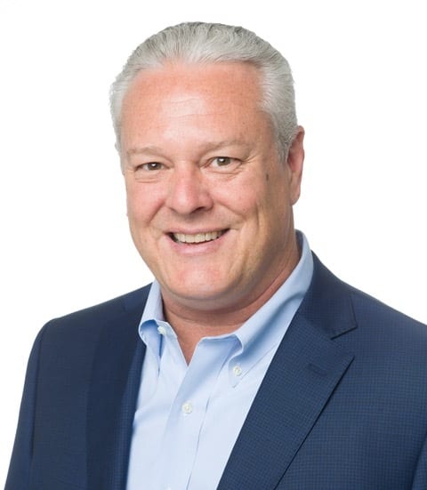 Headshot of a smiling middle-aged man with gray hair wearing a light blue shirt and dark blue suit.