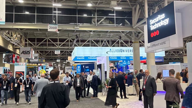 Busy trade show floor with booths for ASIS, AlliedUniversal, and Securitas Technology.