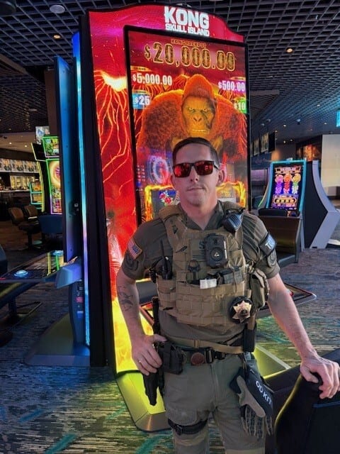Man in tactical gear by a King Kong slot machine in a casino.