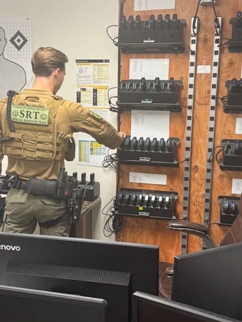 SRT officer in tactical vest placing device in multi-charger rack.