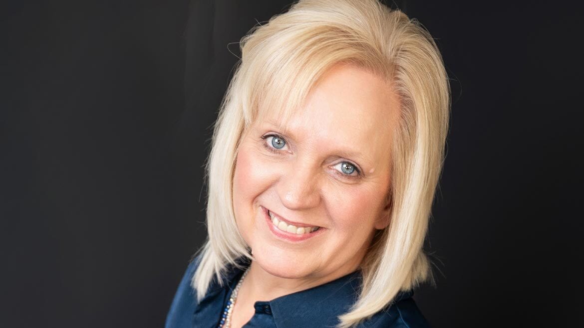 Smiling blonde woman with blue eyes.