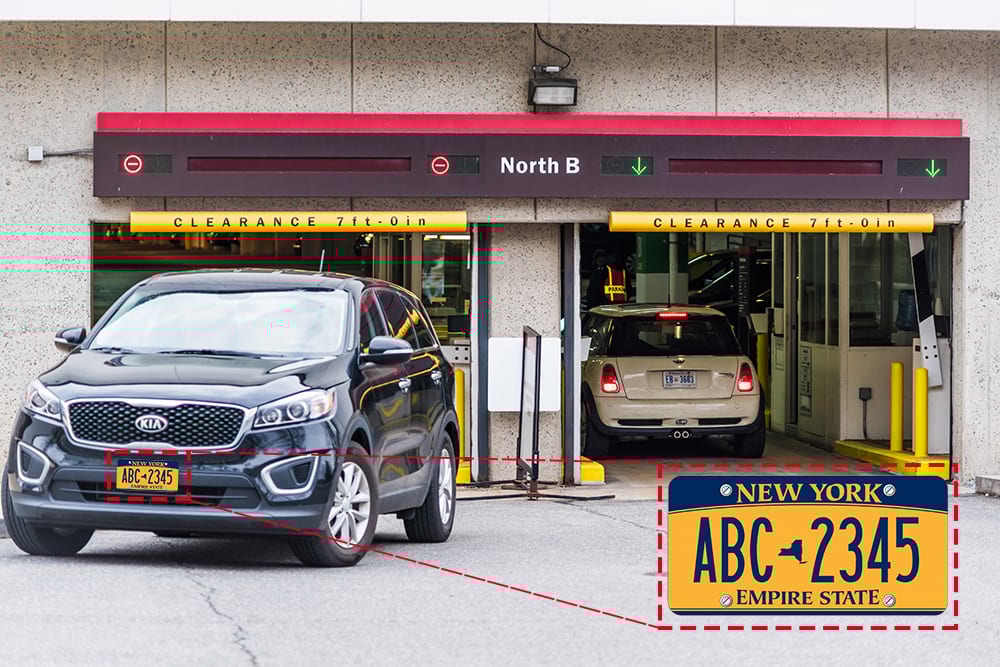 Black SUV and Mini Cooper at a parking garage entrance with clearance signs. A New York license plate is highlighted.