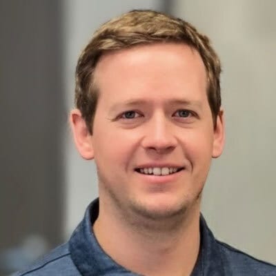 Smiling man with brown hair and blue eyes.