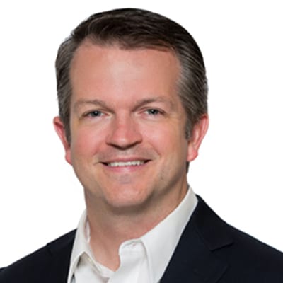 Smiling man in a dark suit jacket and white shirt.