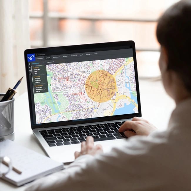 Person on laptop viewing map with a highlighted circular area.