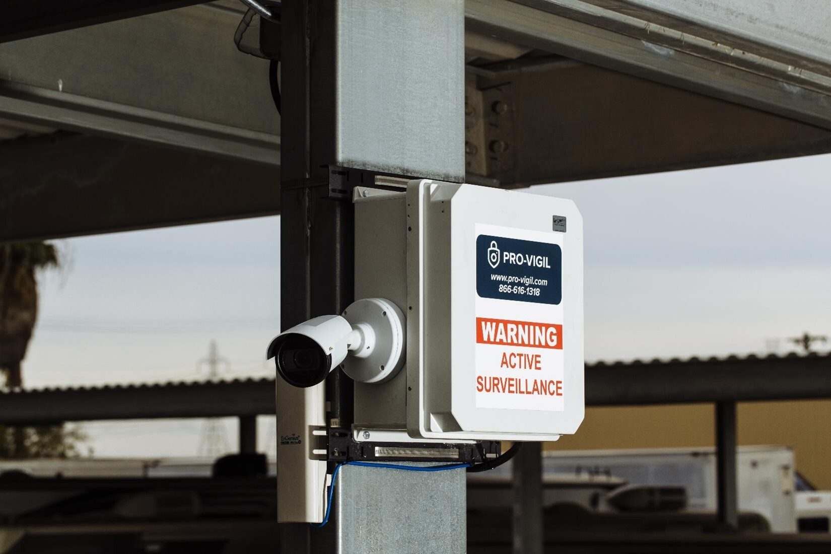 A Pro-Vigil security camera and warning box mounted on a metal pole.