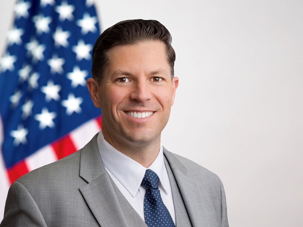 Flag of the United States, Formal wear, Smile, Chin, Eyebrow, Forehead, Collar, Shoulder, Jaw, Blazer