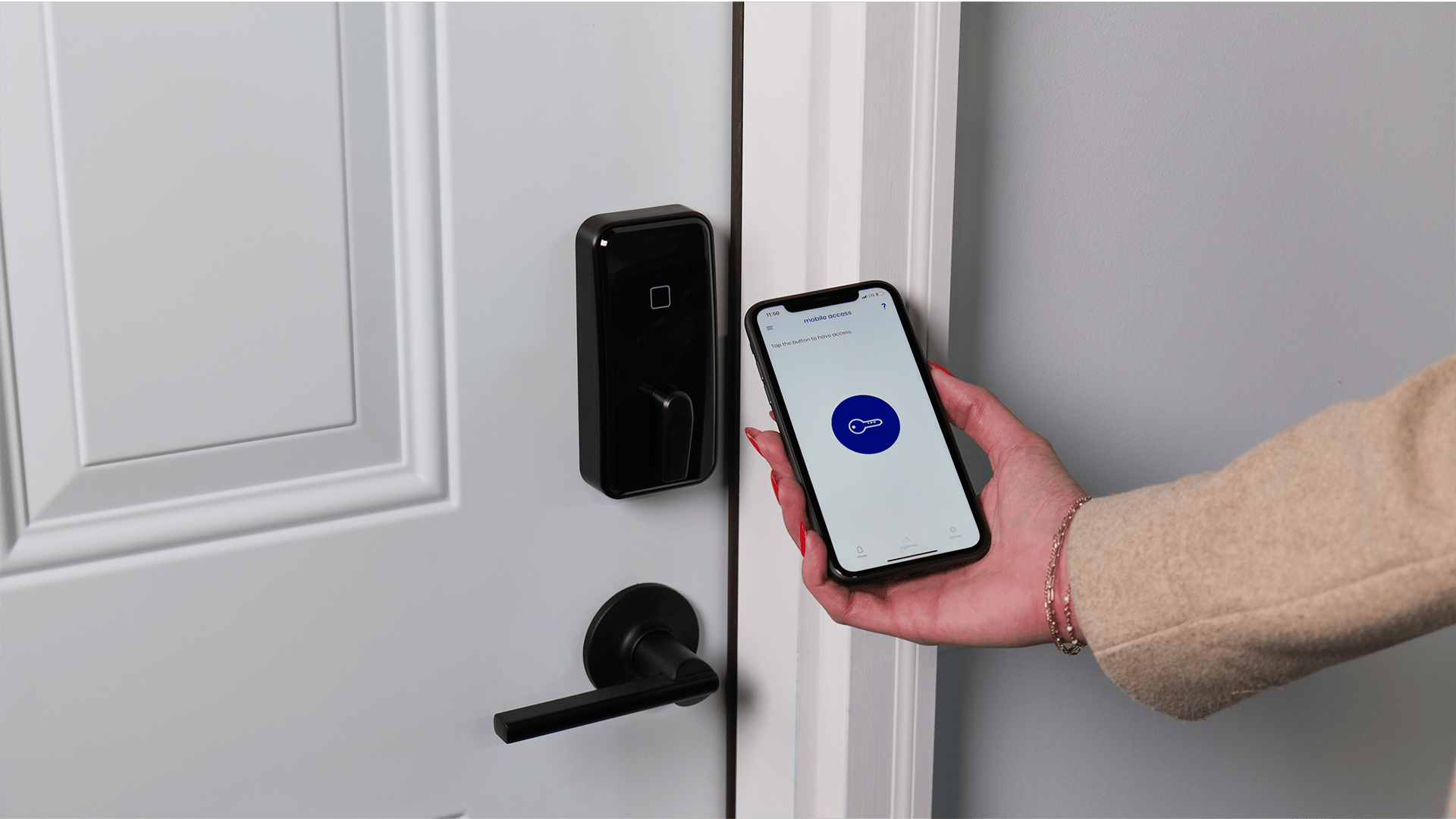 Person using smartphone with mobile access app to operate a smart door lock on a white door.