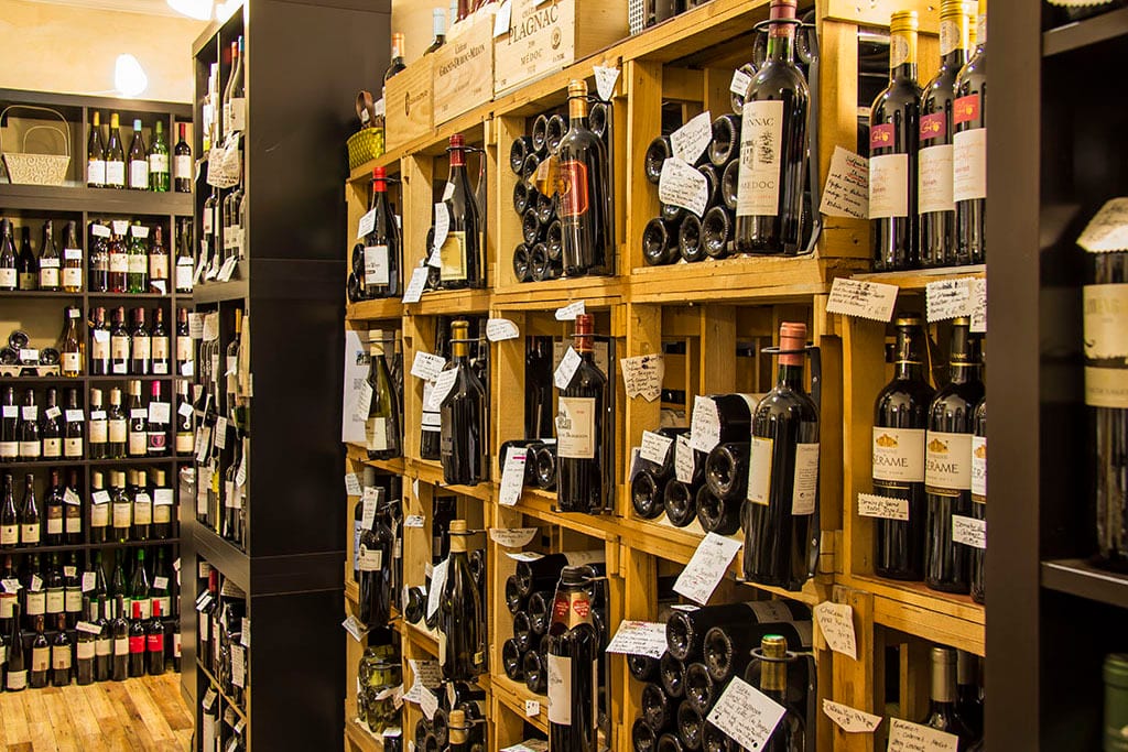 Wine bottles displayed on shelves and in wooden crates in a shop.
