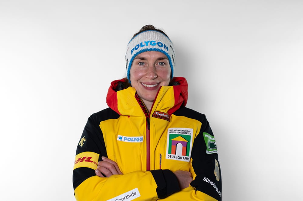 Smiling woman in a yellow and black sports jacket and Polygon beanie.