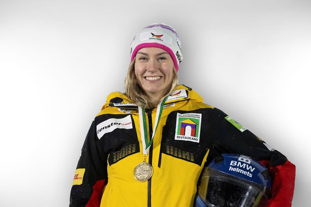 Smiling woman, a winter athlete, with a gold medal and a blue BMW helmet.