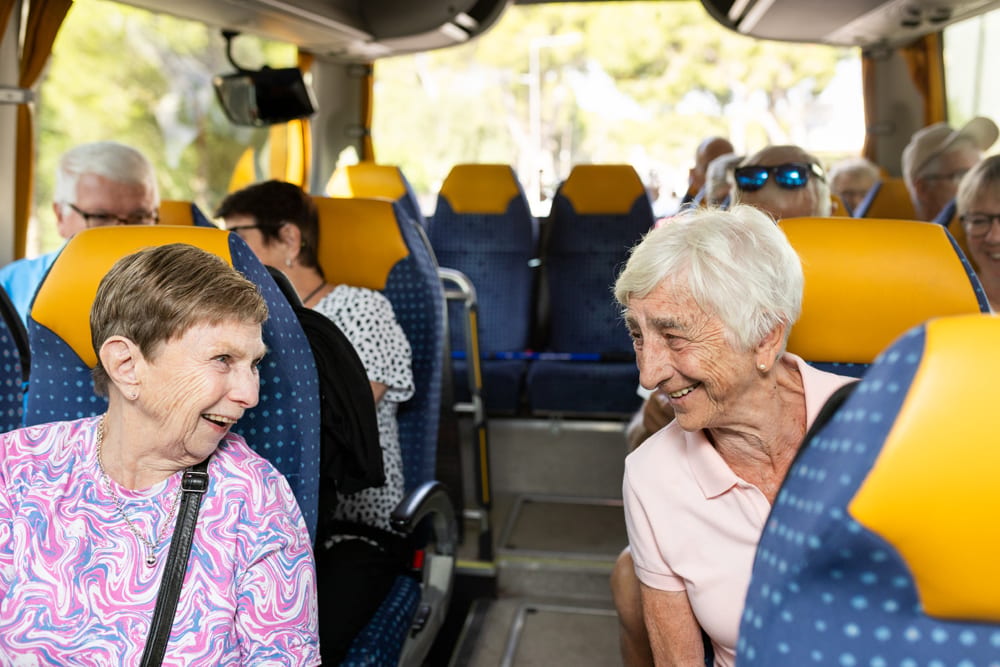 Two happy older women laughing on a bus during a trip, enjoying the journey and each other's company.