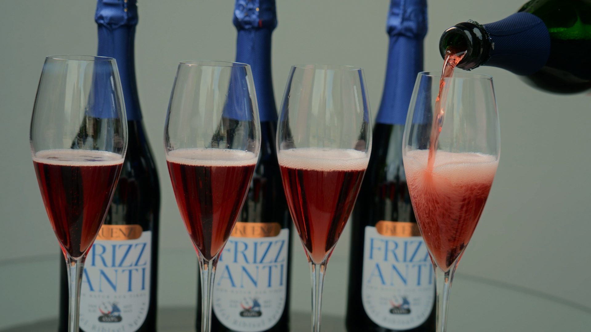 Pink sparkling wine, "Frizzanti" bottles, and glasses with one being poured.