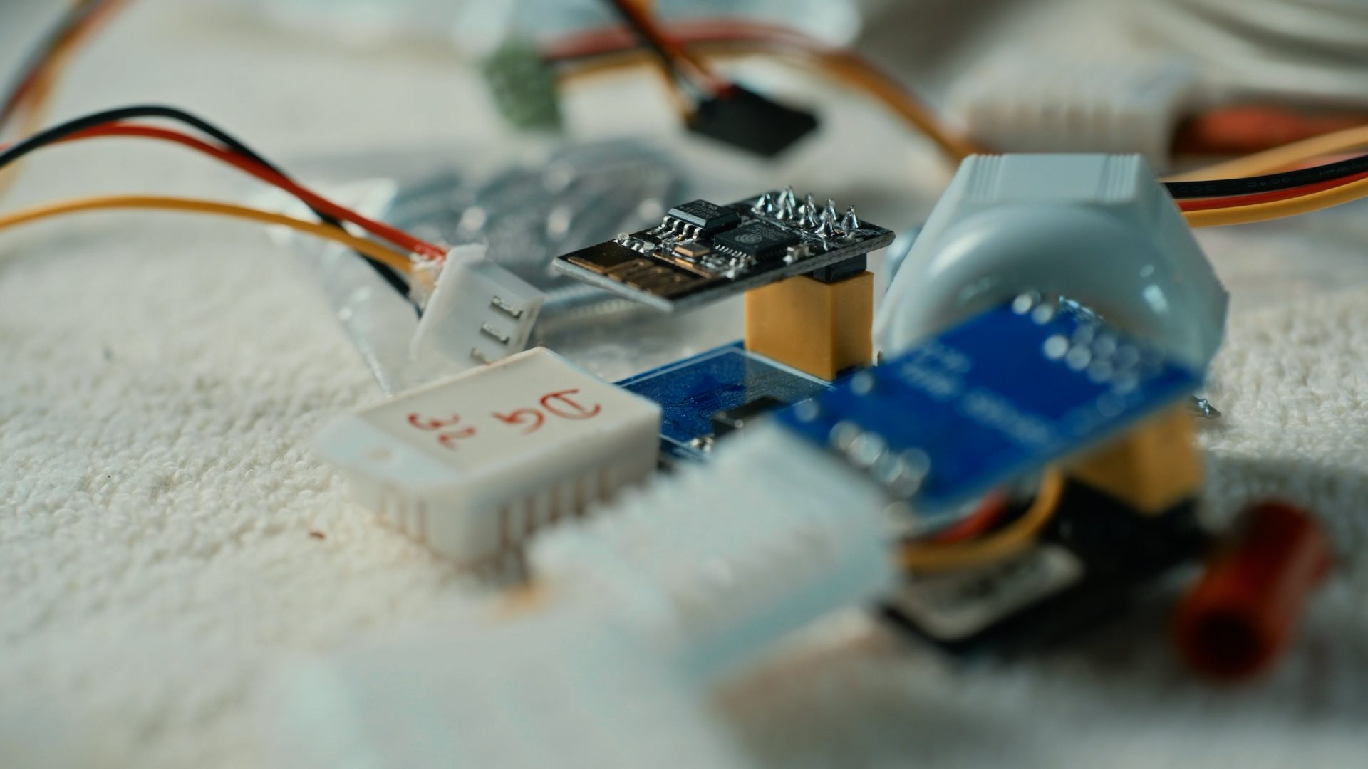 Close-up of various electronic components like sensors, circuit boards, and wires on a textured surface.