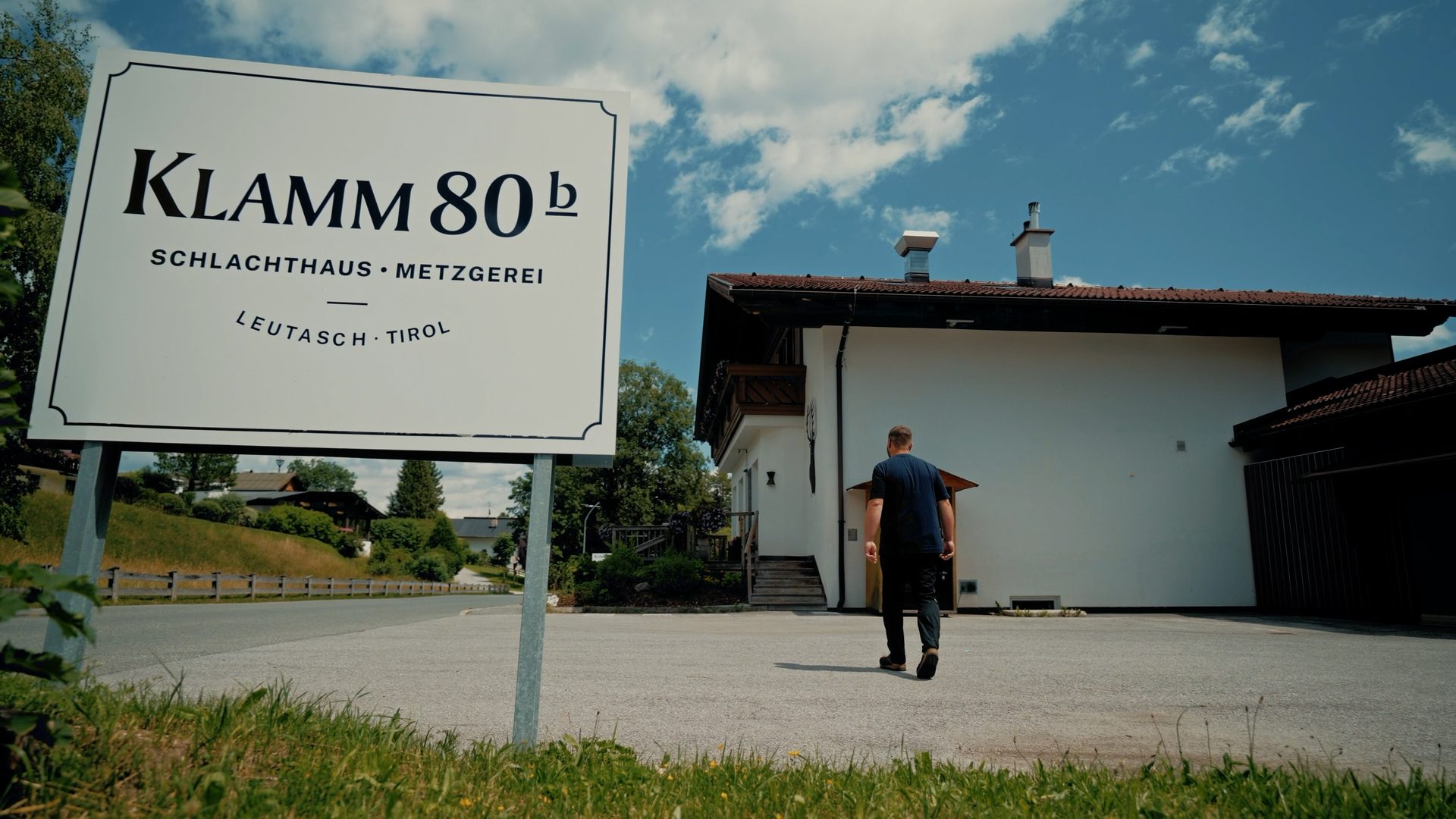 Man walks towards 'KLAMM 80b' butchery and slaughterhouse in Leutasch, Tirol.