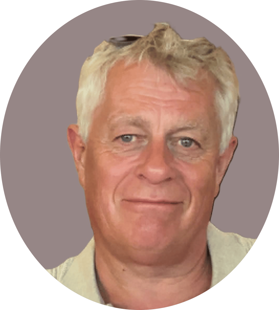 Close-up headshot of a smiling Caucasian man with graying blonde hair against a plain background.