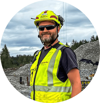 Smiling man in yellow hard hat, sunglasses, and hi-vis vest.