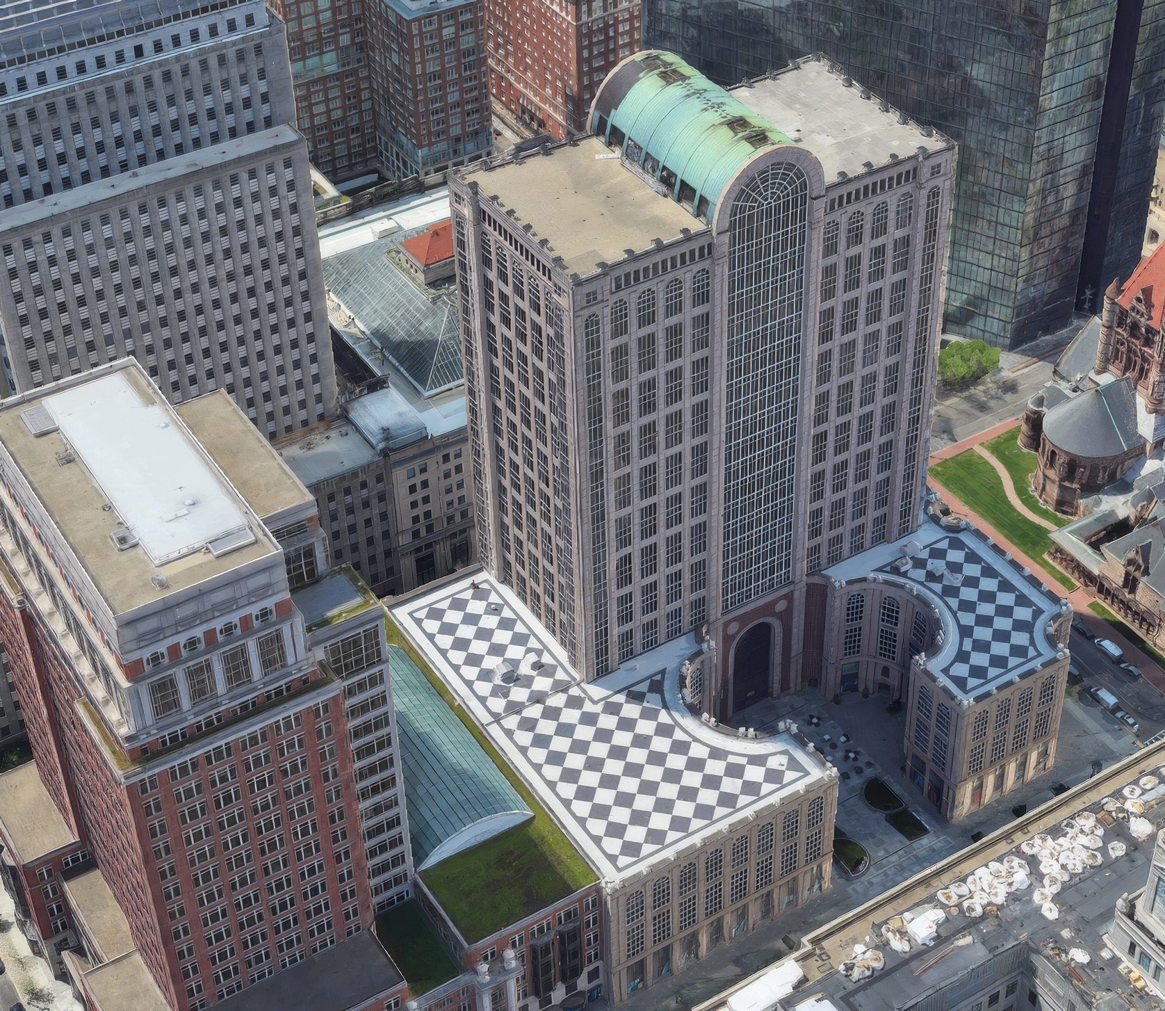 Aerial view of city buildings, featuring a structure with a checkerboard roof and green dome.