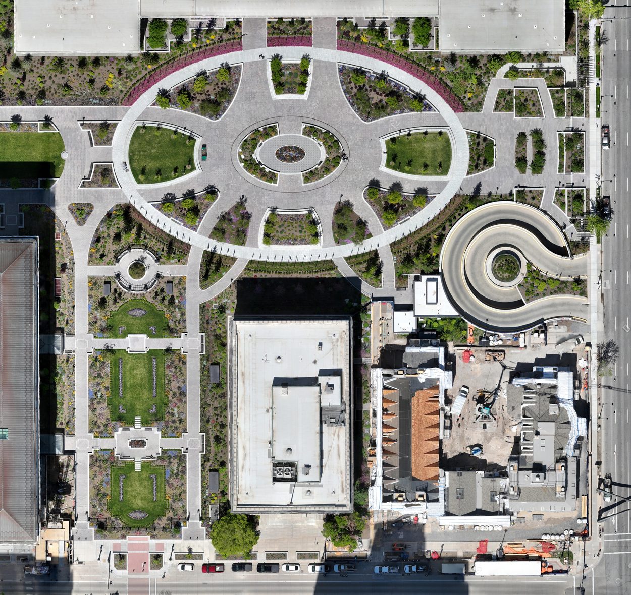 Aerial view of a city block featuring a complex park design, spiral ramp, and various buildings.