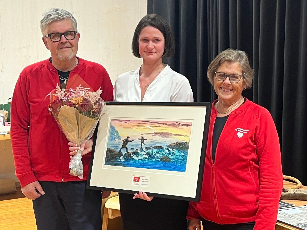Three people holding a framed seascape artwork and a bouquet of flowers.