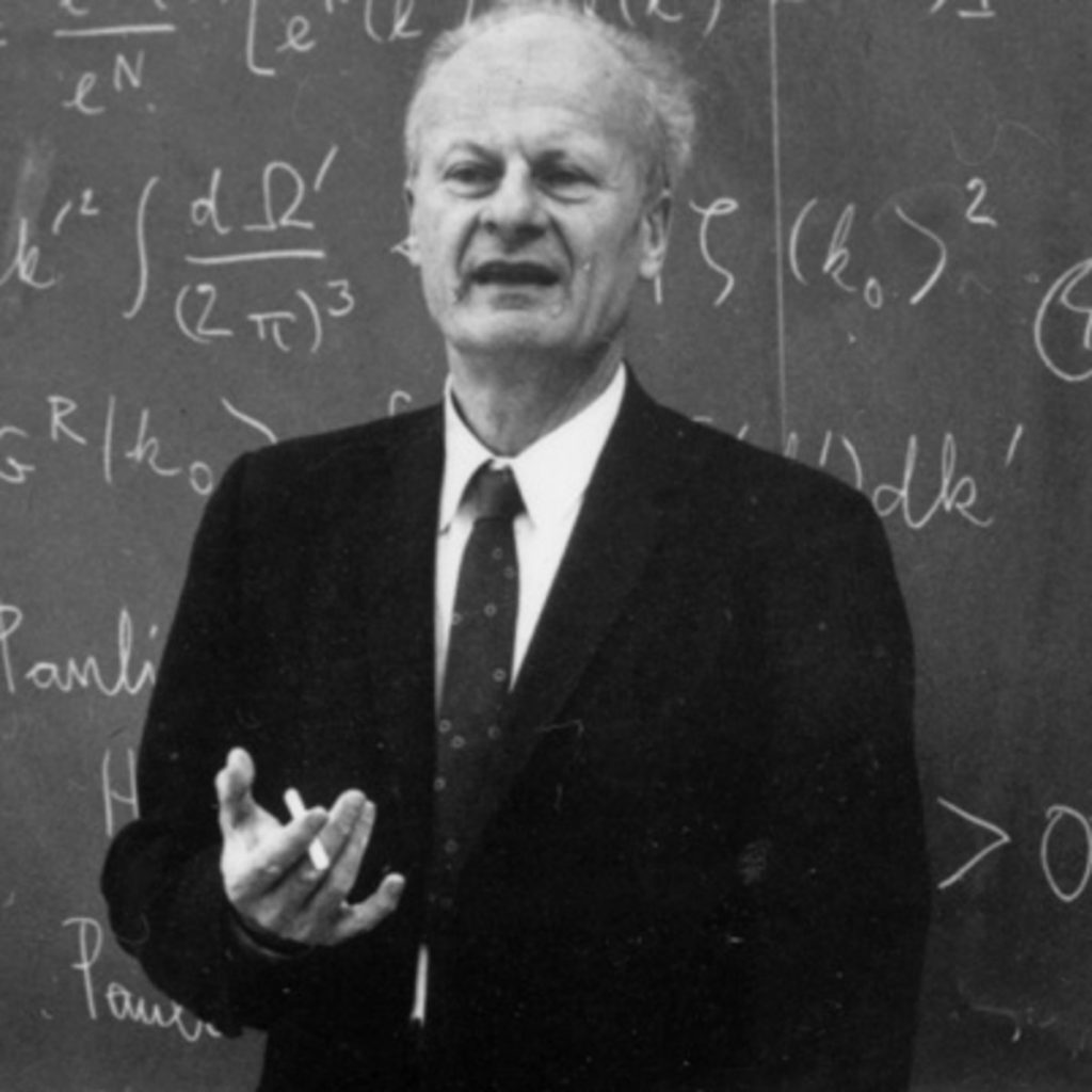 Black and white photo of a professor with a cigarette lecturing in front of a blackboard.